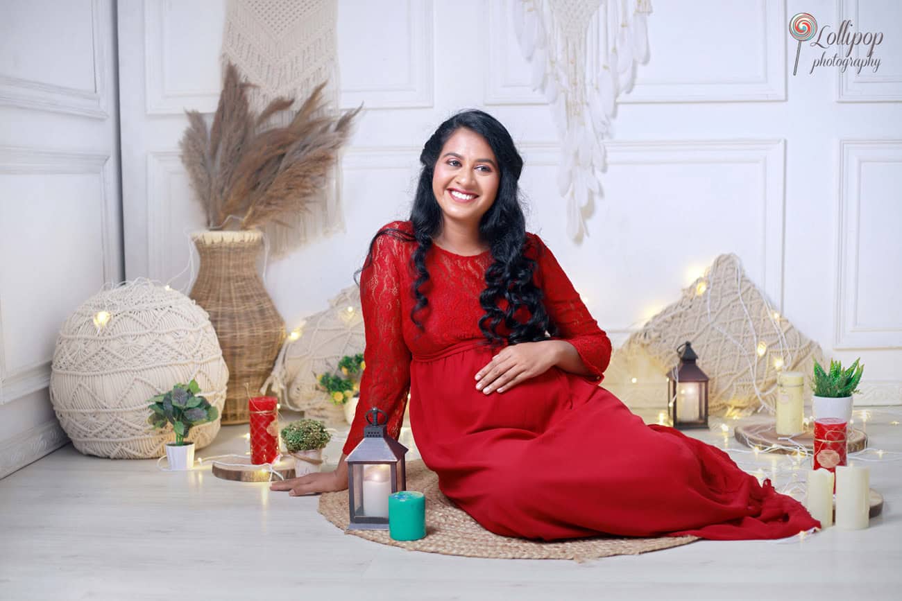 ntimate maternity photo session in Coimbatore showcasing a candlelit setting with warm lighting and an elegant red dress, highlighting the beauty of expectancy.