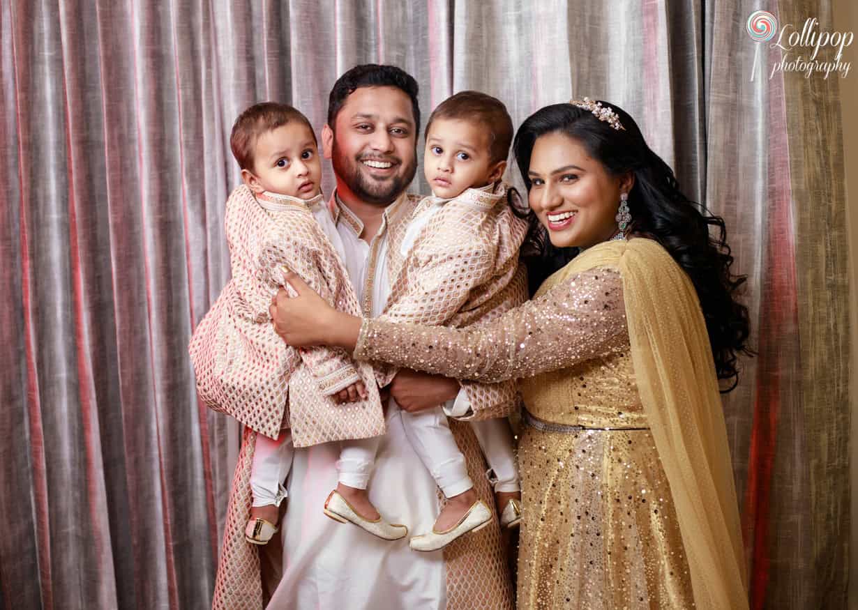 Cheerful family of four with twin toddlers dressed in ornate traditional outfits, sharing a joyful moment during a photoshoot in Chennai